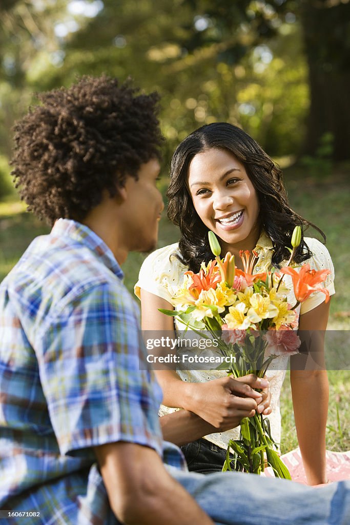 Man giving smiling woman bouquet of flowers.