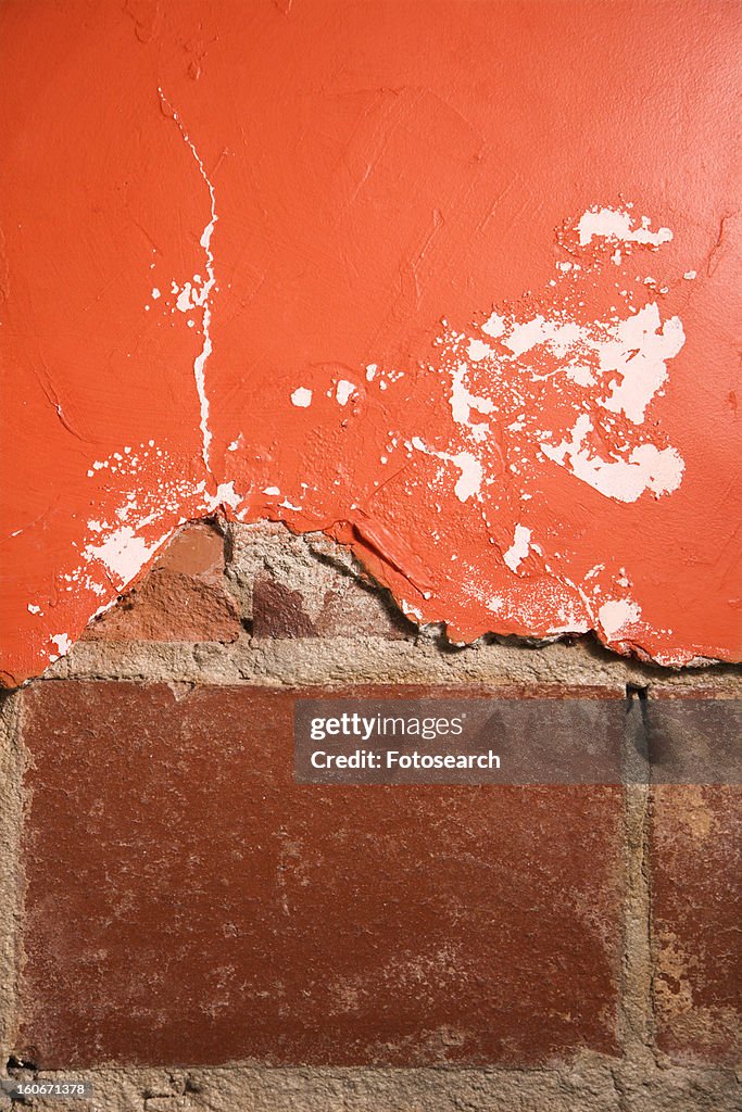 Red wall with cracking plaster and brick