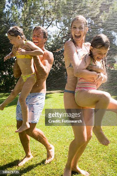 family at home playing in garden - shower man woman washing foto e immagini stock