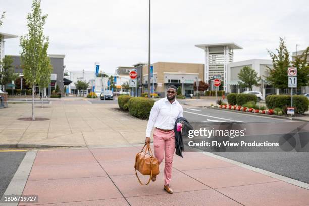 man on business trip walks across street carrying luggage - duffel tas stockfoto's en -beelden