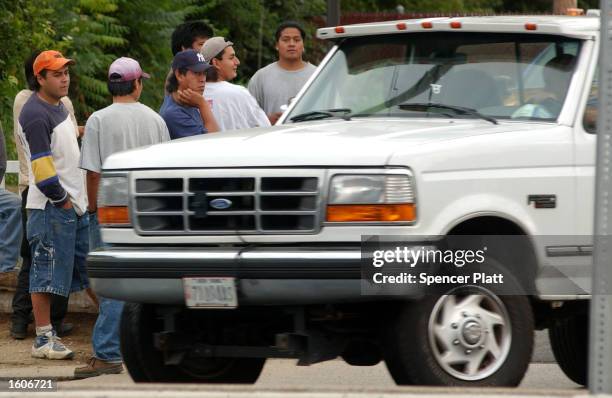 Day laborers, mostly undocumented Mexican immigrants, wait for work on a street corner August 3, 2001 in Farmingville, New York. Many residents of...