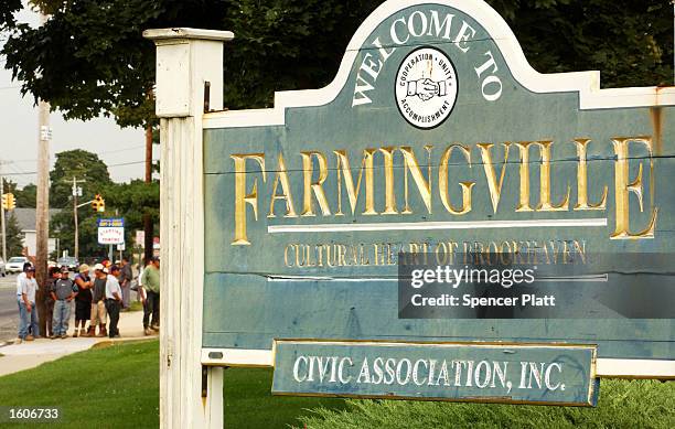 Sign welcomes people to Farmingville, New York August 3, 2001 while day laborers, mostly undocumented Mexican immigrants, wait for work on the street...