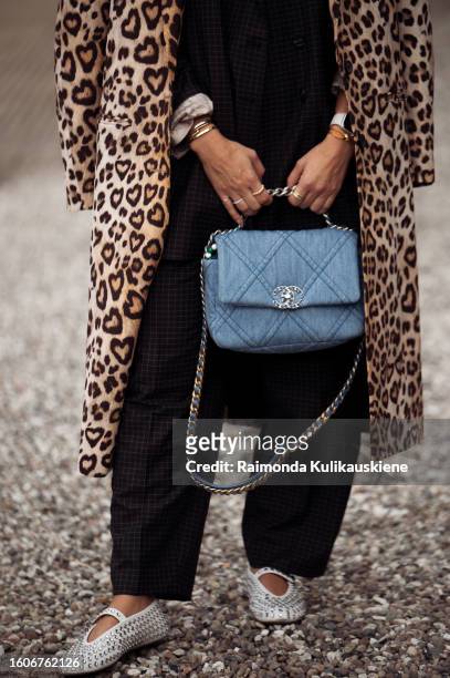 Karin Teigl wears a cap, Chanel bag in a blue, black oversized blazer, pants, and coat with animal print outside Munthe during the Copenhagen Fashion...