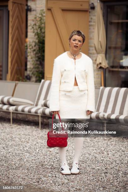 Emma Fridsell wears white tights, a red bag, a white mini skirt, and a matching cropped jacket outside Munthe during the Copenhagen Fashion Week...