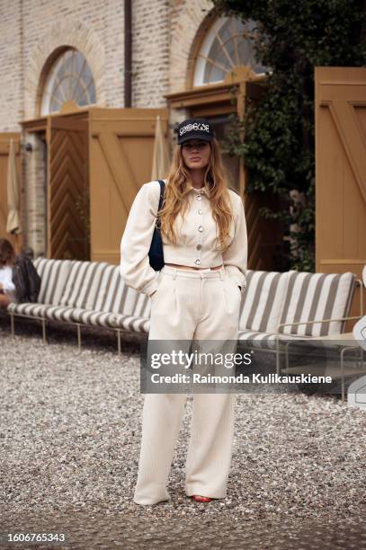 Lois Schindeler wears beige wide pants, matching buttoned-up crop top, black LOEWE hat, and black bag outside Munthe during the Copenhagen Fashion...