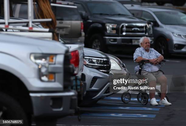 Resident sits in his wheelchair in the parking of King's Cathedral Maui on August 10, 2023 in Kahului, Hawaii. Dozens of people were killed and...