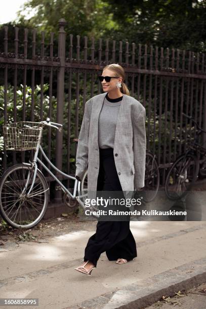 Tine Andrea Lauvli wears black wide pants, grey sweater and grey jacket outside Mark Kenly Domino Tan during the Copenhagen Fashion Week...