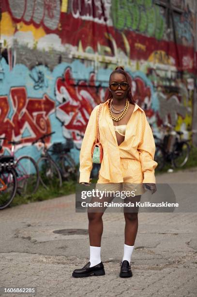 Trish Beghin wears, an orange striped shirt, shorts, white socks, and black shoes outside Gestuz during the Copenhagen Fashion Week Spring/Summer...