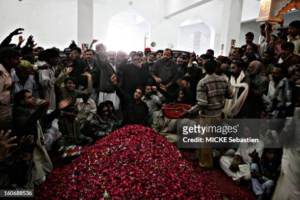 Bilawal Bhutto , kneel, making a last visit to his mother's grave, covered with red rose petals, raising a fist avenging mausoleum in Ghari Khuda...