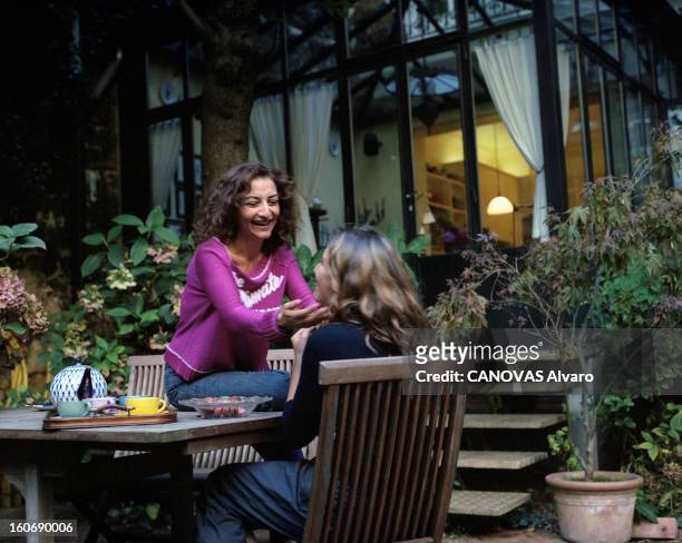 Sonia Rykiel With Family. Paris - 28 septembre 2000 - Nathalie RYKIEL chez elle, en sweat-shirt et pantalon en jean, assise sur une table dans le...