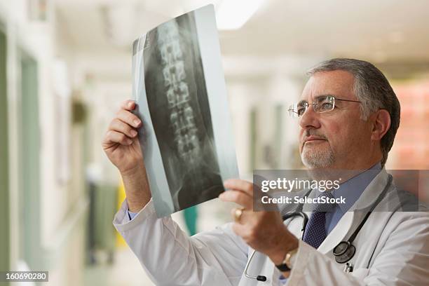 médico mirando en las radiografías de edad avanzada - columna vertebral humana fotografías e imágenes de stock