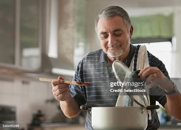 elderly man cooking - man cooking at home stock pictures, royalty-free photos & images