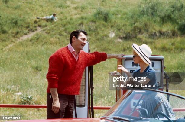 Shooting Of The Film 'le Mepris' By Jean-luc Godard. Jack PALANCE et Brigitte BARDOT discutant devant une station essence pendant le tournage du film...