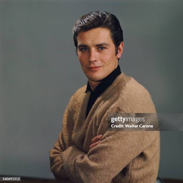 Close-up Of Alain Delon. Photo studio : plan de face souriant d'Alain DELON les bras croisés sur fond gris.