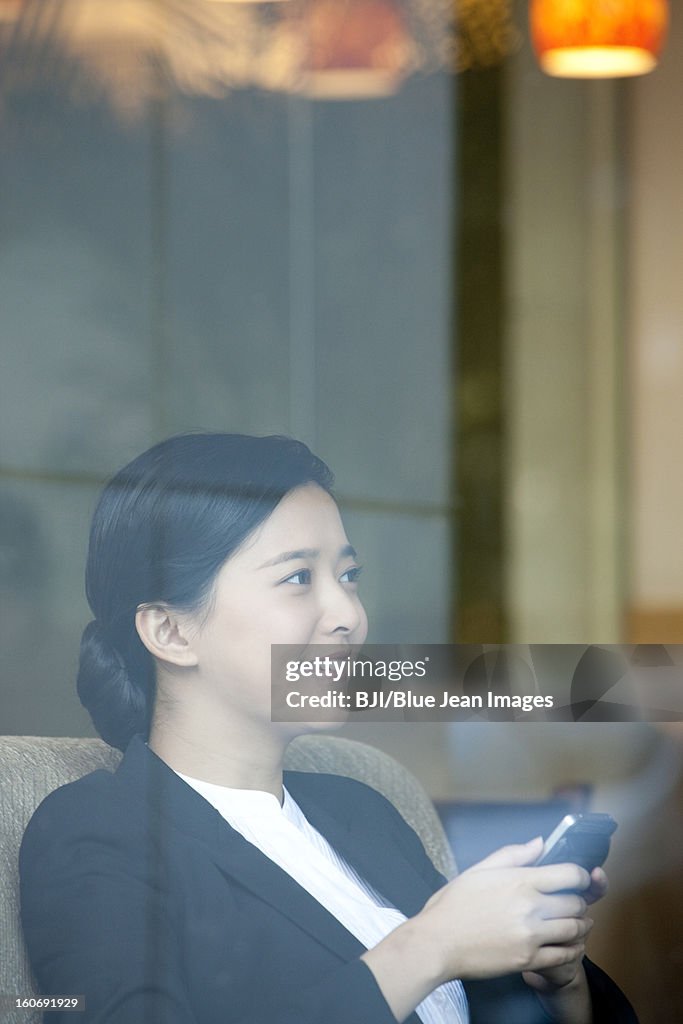 Cheerful businesswoman with smart phone in cafe