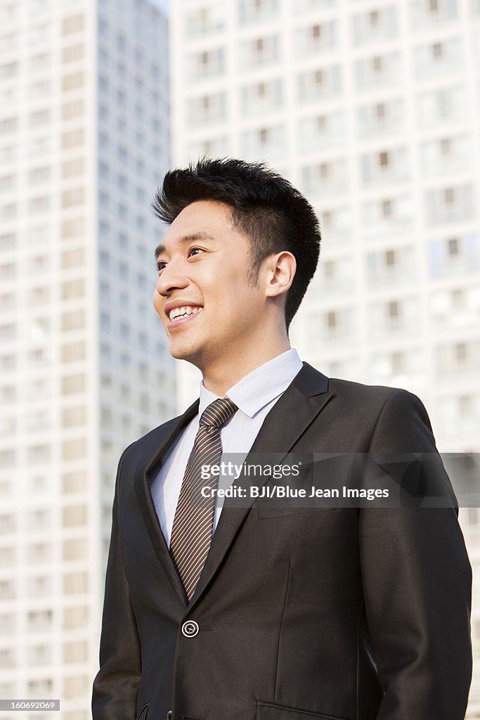 Happy young businessman looking at view in downtown district