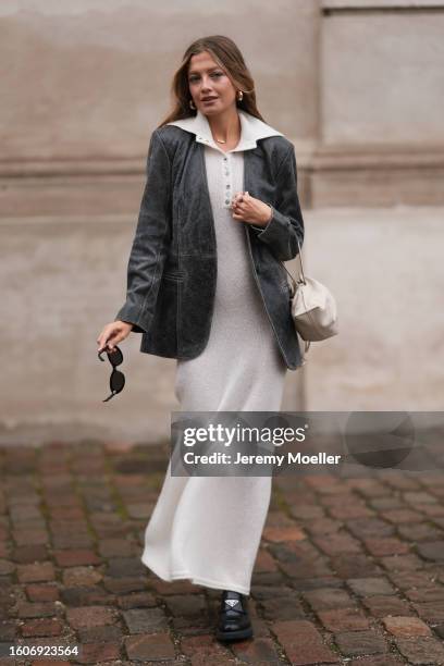 Zoë Pastelle is seen wearing a cream white wool knit zip collar long dress, black washed leather blazer jacket, latte white and cream leather pouch...