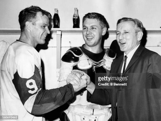 Gordie Howe and Alex Delvecchio of the Detroit Red Wings celebrate in the locker room with head coach Sid Abel after defeating the Chicago Blackhawks...