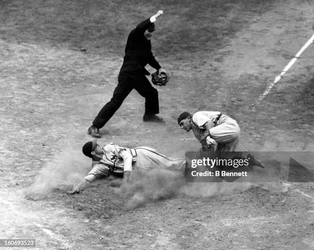 Stan Musial of the St. Louis Cardinals is tagged out at home by catcher Bruce Edwards of the Brooklyn Dodgers as home plate umpire Babe Pinelli makes...