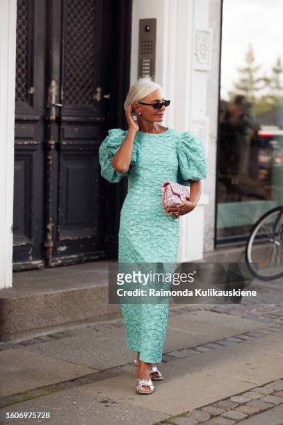 Grece Ghanem wears black sunglasses, a long teal dress with puffy sleeves, and a pink Chanel bag outside Rotate during the Copenhagen Fashion Week...