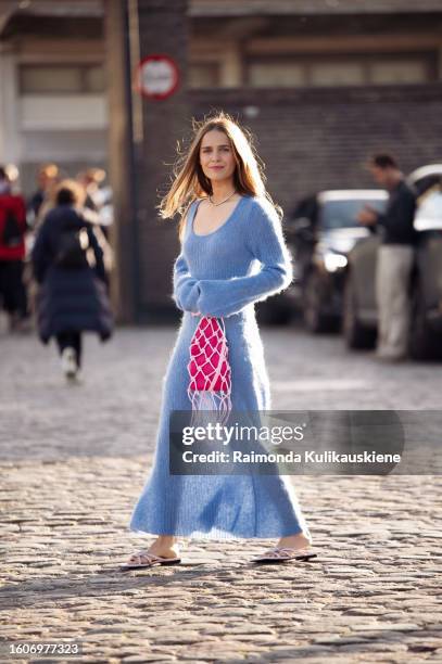 Guest wears a blue knitted maxi dress and pink bag outside Ganni during the Copenhagen Fashion Week Spring/Summer 2024 on August 10, 2023 in...