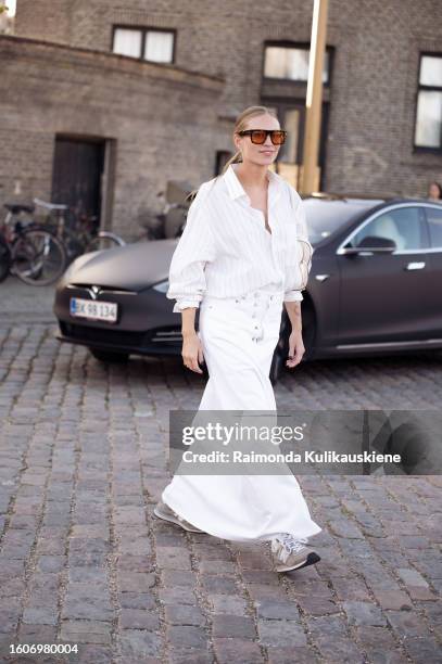 Tine Andrea Lauvli wears white long denim maxi skirt, white shirt, and white bag outside Ganni during the Copenhagen Fashion Week Spring/Summer 2024...