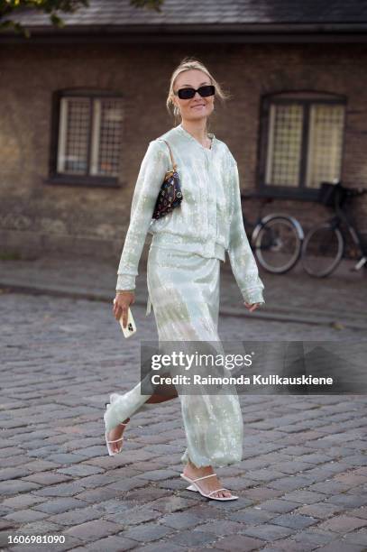 Guest wears light green sequin long m axi skirt and matching long-sleeve top and a black bag outside Ganni during the Copenhagen Fashion Week...