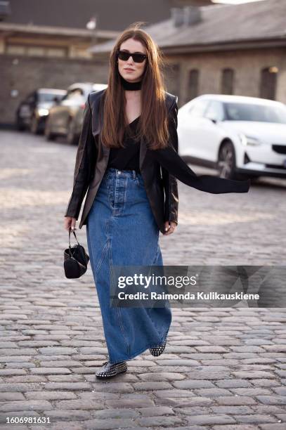Annabel Rosendahl wears a long blue denim maxi skirt, black top, black leather jacket, and black choker outside Ganni during the Copenhagen Fashion...