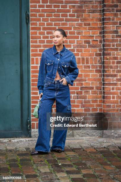 Guest wears gold earrings, a navy blue denim buttoned jacket, matching navy blue denim cargo large pants, a green matte leather handbag, dark brown...