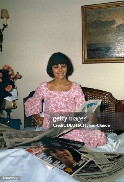 Close-up Of Mireille Mathieu In Gdr . RDA-1972 - Mireille MATHIEU, assise sur le lit de sa chambre d'hôtel, souriante, en chemise de nuit à fleurs...