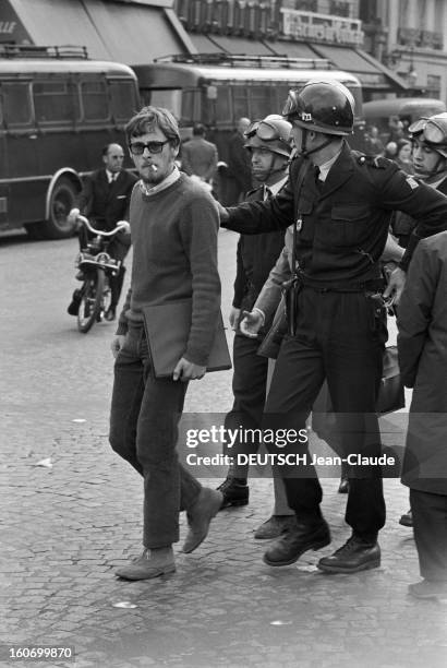 Riots In Latin Quarter. Paris - 12 juin 1968 - Dans une rue du Quartier Latin, un homme tenant un classeur à la main, portant des lunettes de soleil...