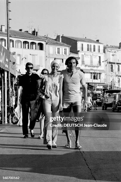 Naiads Are Back. Saint-Tropez, 30 juin 1971- Reportage sur les naïades de la plage: un jeune couple, lui en short, elle vêtue de blanc et coiffée...