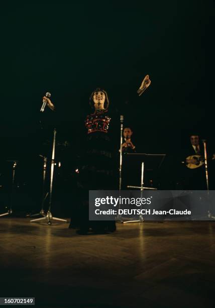 Close-up Of Mireille Mathieu In Gdr . RDA-1972 - Portrait de Mireille MATHIEU, souriant et chantant micro en main, bras écartés, vêtue d'une longue...