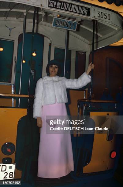 Close-up Of Mireille Mathieu In Gdr . RDA-1972 - Mireille MATHIEU, vêtue d'une courte veste de fourrure blanche sur robe longue rose, se tient à un...