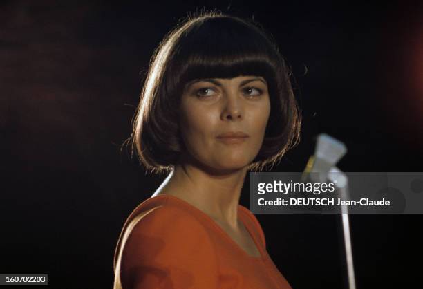 Close-up Of Mireille Mathieu In Gdr . RDA- 1972- Mireille MATHIEU, vêtue d'une longue robe orange à manches longues, chante sur scène, visage tourné...