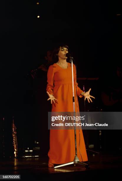 Close-up Of Mireille Mathieu In Gdr . RDA- 1972- Mireille MATHIEU, vêtue d'une longue robe orange à manches longues, chante debout, mains ouvertes,...