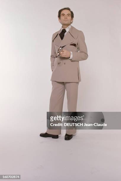Men's Fashion. France- Paris - 1973- Les ténors de la haute couture: Pierre CARDIN, pose debout, une paire de lunettes dans sa main gauche, en...
