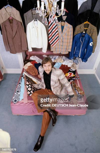 Men's Fashion. France- Paris - 1973- Jean-Claude BOUTTIER, boxeur français, pose assis sur un lit recouvert de cravates chamarées et de chemises,...