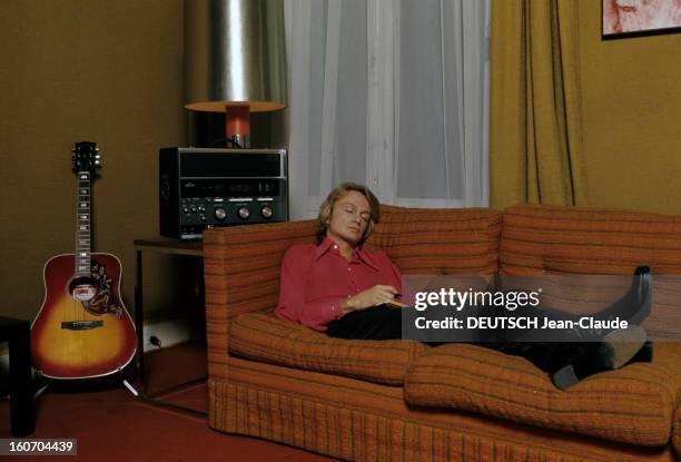 Claude Francois Ceo. En France, en janvier 1973, allongé sur un canapé orange, devant une guitare, vêtu d'une chemise rose et d'un pantalon noir, le...