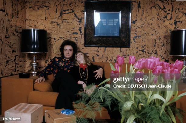 Close-up Of Michel Sardou. En France, en mars 1974, chez lui dans sa maison, dans un pièce tapissée de liège, assis sur un canapé orange, devant une...