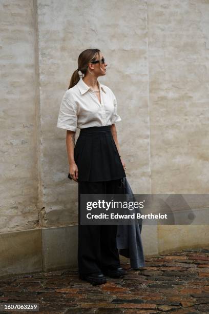 Guest wears black sunglasses, a white latte short sleeves shirt, a black short skirt, black pants, a dark gray cropped blazer jacket, black shiny...