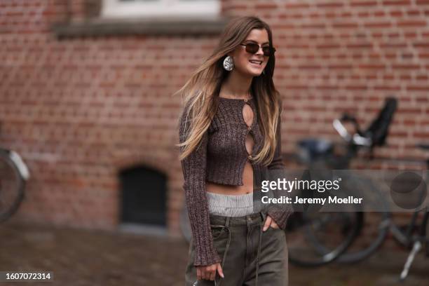 Guest seen outside Skall Studio show wearing dark brown sunnies, big silver earrings, brow buttoned up top, oversized washed out brown pair of jeans,...