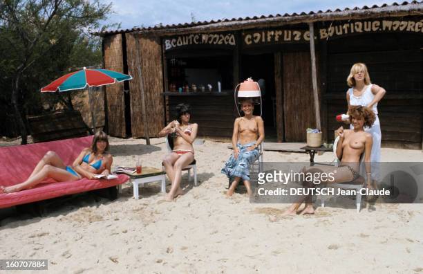 The Big Names Of Hairdressing. France - 1976 - Sur une plage, devant un salon de coiffure installé dans une cabane en canisses, de gauche à droite :...