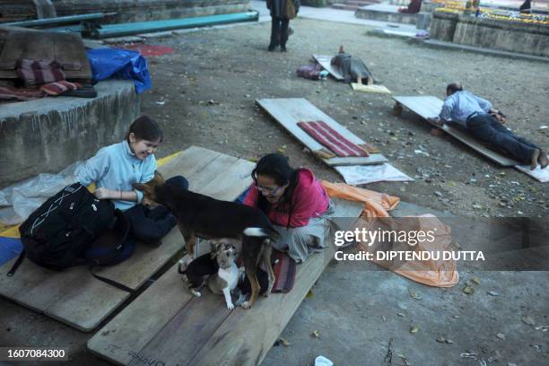 Devotees watch stray dogs as they meditates at Mahabodhi temple premises as Tibetan Spiritual Leader The Dalai Lama delivers his teachings during the...