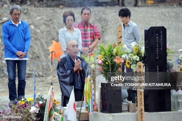 Relatives of some of the victims look on as a Buddhist monk prays at an alter set up in front of Okawa elementary school in the city of Ishinomaki,...