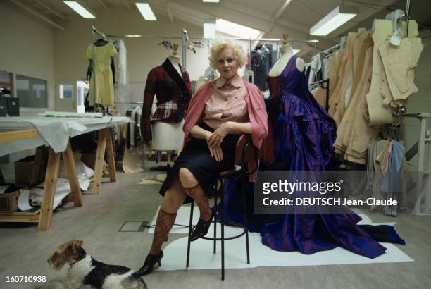 Vivienne Westwood, English Designer. A Londres, dans son atelier de BATTERSEA, Vivienne WESTWOOD, en jupe avec des chaussettes fines, posant assise...