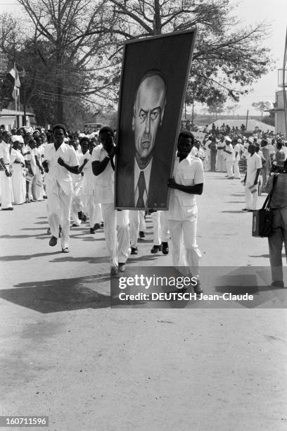 Official Visit Of Valery Giscard D'estaing In Guinea. Guinée, décembre 1978. Deux guinéens portent un portrait du Président de la République...