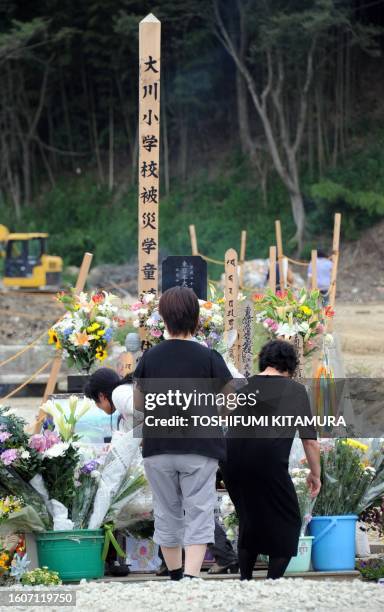 Relatives of the tsunami victims at Okawa elementary school pray place flowers and pray at an altar set up in front of the school in the city of...