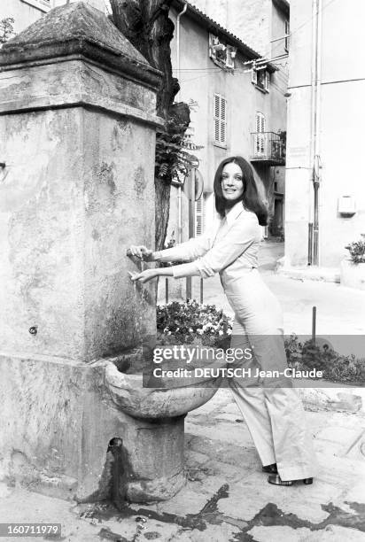 Summer 1971 Fashion In Saint-tropez. A Saint-Tropez, la comédienne Ewa SWANN, prenant de l'eau à une fontaine, portant un pantalon de jeans blanc et...