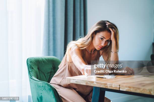 woman with post traumatic stress  disorder drinking pills on the kitchen. woman with head in hands sit at the table - hålla huvudet i händerna bildbanksfoton och bilder